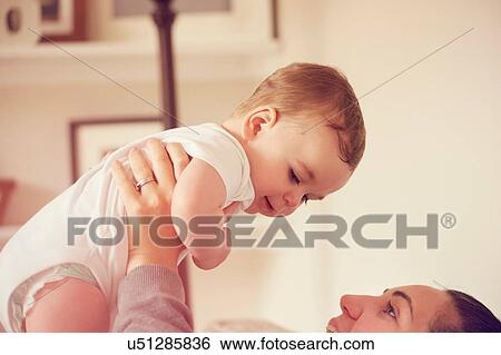 Stock Photograph - Mother and baby boy playing in living room. Fotosearch
