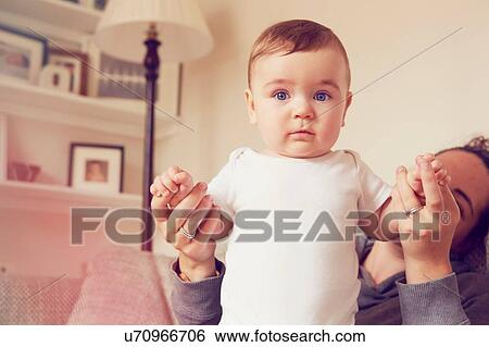 Stock Photograph - Mother and baby boy playing in living room. Fotosearch