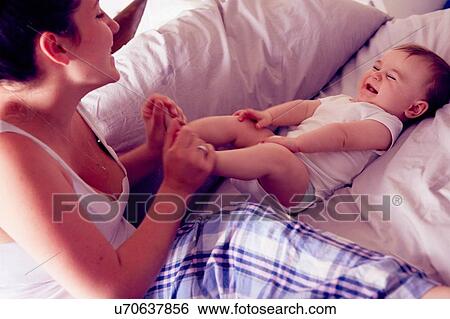 Mother and baby boy playing on bed View Large Photo Image Stock Photograph - Mother and baby boy playing on bed. Fotosearch