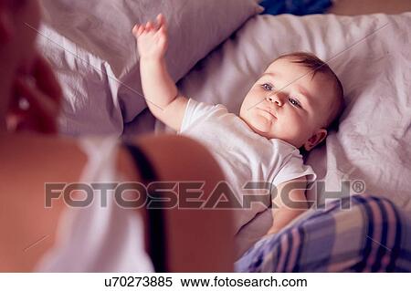 Stock Photography - Mother and baby boy playing on bed. Fotosearch