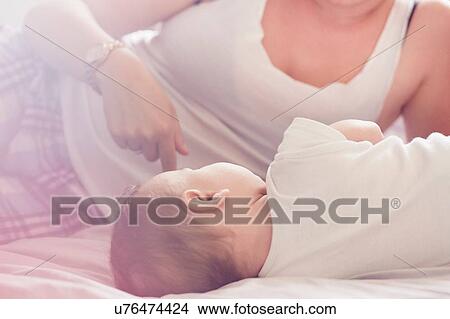 Picture - Mother and baby boy resting on bed. Fotosearch
