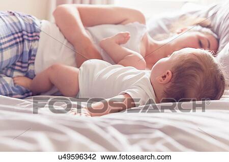 Mother and baby boy resting on bed View Large Photo Image Stock Image - Mother and baby boy resting on bed. Fotosearch