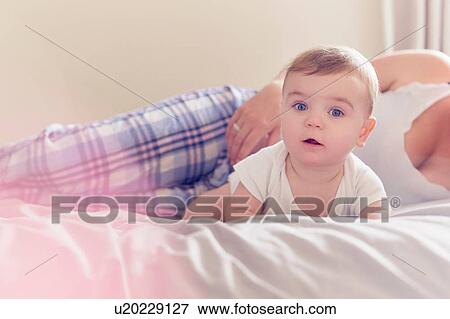 Stock Photo - Mother and baby boy resting on bed. Fotosearch