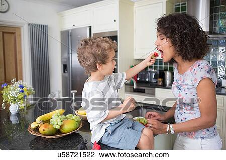 "Mother and son in kitchen, sharing fruit" View Large Photo Image Stock Image - "Mother and son in kitchen, sharing fruit". Fotosearch