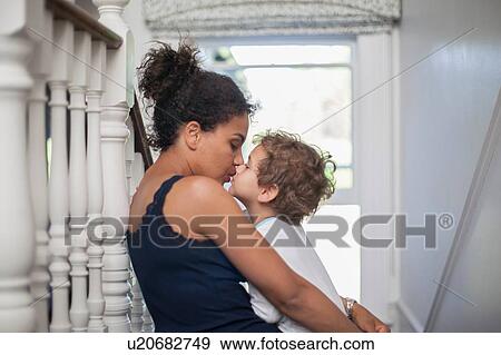 Stock Photo - "Mother and son sitting on stairs, son kissing mother". Fotosearch