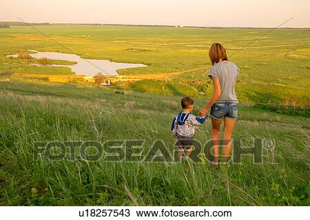 "Mother and son, walking through field at sunset, rear view" View Large Photo Image Stock Image - "Mother and son, walking through field at sunset, rear view". Fotosearch