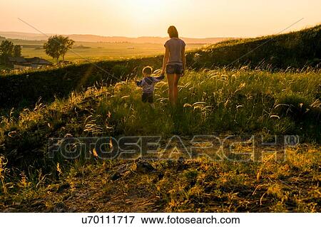 "Mother and son, walking through field at sunset, rear view" View Large Photo Image Stock Photo - "Mother and son, walking through field at sunset, rear view". Fotosearch
