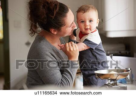 Mother holding baby boy on kitchen counter View Large Photo Image Picture - Mother holding baby boy on kitchen counter. Fotosearch