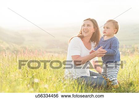 Stock Photograph - Mother sitting with young son in field. Fotosearch