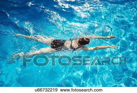 Stock Photo - Overhead view of mature woman swimming in swimming pool. Fotosearch