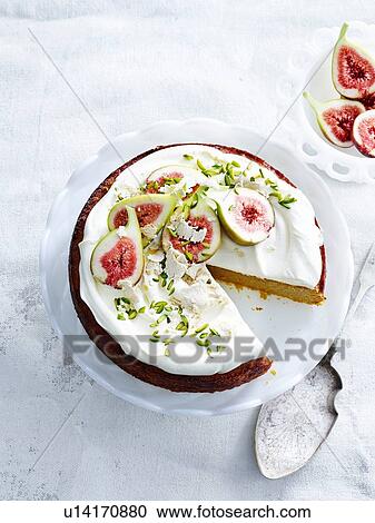 Stock Image - "Overhead view of orange and almond cake with yoghurt cream, pistachios, figs and cake server". Fotosearch