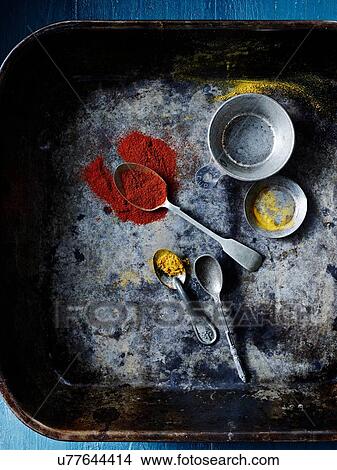 Picture - Overhead view of spoofuls of tumeric and paprika spices on baking tin. Fotosearch