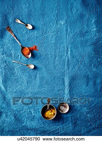 Stock Image - Overhead view of spoofuls of tumeric and paprika spices on blue background. Fotosearch