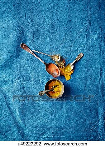 Stock Image - Overhead view of spoofuls of tumeric and paprika spices on blue background. Fotosearch