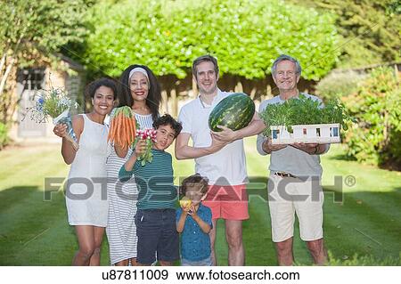 Stock Photo - "Portrait of family in garden, holding home grown produce". Fotosearch