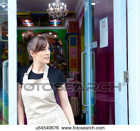 Stock Photograph - "Portrait of female worker in cake shop, standing in doorway of shop, looking out". Fotosearch