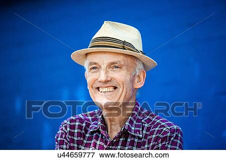 Stock Photo - "Portrait of happy senior man, blue brick wall in background". Fotosearch