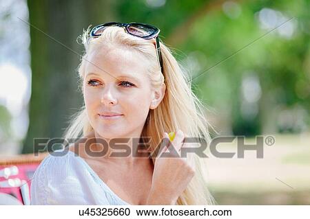 Portrait of long haired blonde young woman with sunglasses on head looking away smiling View Large Photo Image Stock Image - Portrait of long haired blonde young woman with sunglasses on head looking away smiling. Fotosearch
