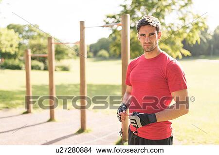 Picture - "Portrait of mid adult man in park, preparing for workout". Fotosearch