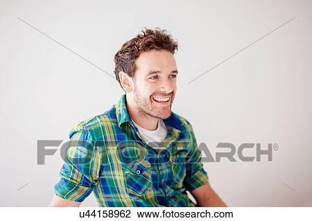 Portrait of mid adult man wearing checked shirt looking away smiling View Large Photo Image Stock Image - Portrait of mid adult man wearing checked shirt looking away smiling. Fotosearch