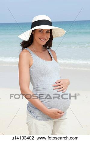 Portrait of pregnant mid adult woman wearing sunhat on beach View Large Photo Image Stock Image - Portrait of pregnant mid adult woman wearing sunhat on beach. Fotosearch