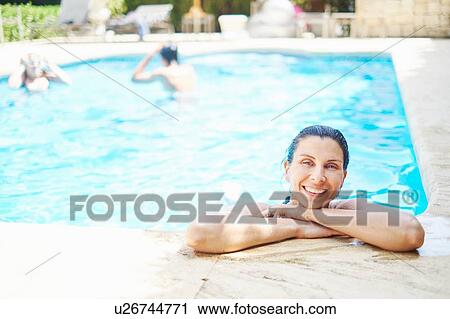 Stock Image - Portrait of smiling mature woman with wet hair in swimming pool. Fotosearch
