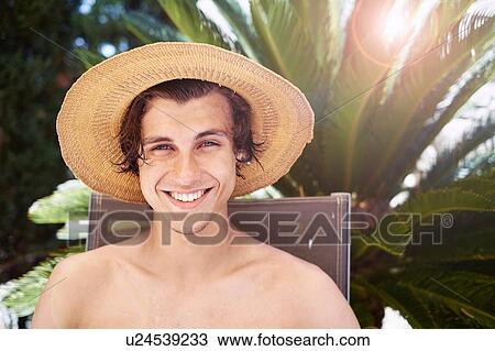 Stock Image - Portrait of smiling young man wearing sunhat. Fotosearch