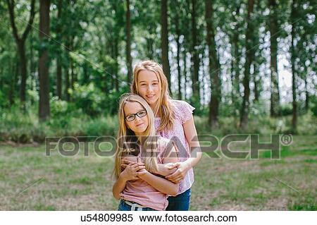 Stock Photography - "Portrait of two young girls in field, smiling". Fotosearch