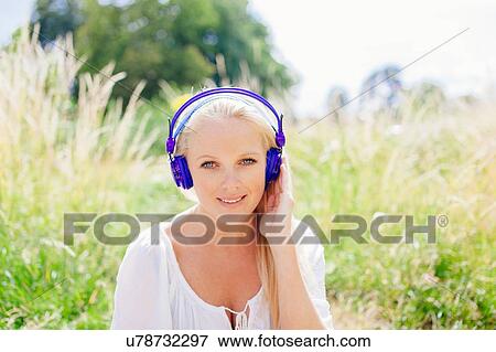 Portrait of young blonde woman wearing headhones looking at camera smiling View Large Photo Image Stock Photo - Portrait of young blonde woman wearing headhones looking at camera smiling. Fotosearch