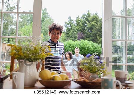 "Portrait of young boy standing by patio doors, family standing behind him in garden" View Large Photo Image Stock Photo - "Portrait of young boy standing by patio doors, family standing behind him in garden". Fotosearch
