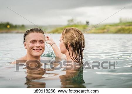 Stock Photo - "Portrait of young couple splashing in Secret Lagoon hot spring (Gamla Laugin), Fludir, Iceland". Fotosearch