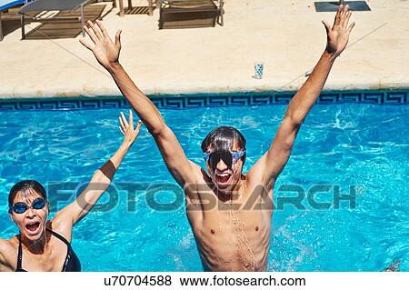Stock Photo - Portrait of young man and mother with hands raised in swimming pool. Fotosearch