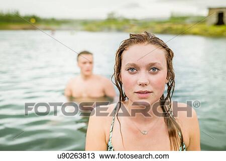 "Portrait of young woman standing in front of boyfriend in Secret Lagoon hot spring (Gamla Laugin), Fludir, Iceland" View Large Photo Image Stock Image - "Portrait of young woman standing in front of boyfriend in Secret Lagoon hot spring (Gamla Laugin), Fludir, Iceland". Fotosearch