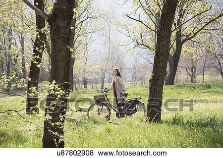 Portrait of young woman with bicycle in rural woodland View Large Photo Image Stock Photo - Portrait of young woman with bicycle in rural woodland. Fotosearch