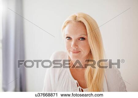 Stock Image - Portrait of young woman with long blond hair looking at camera smiling. Fotosearch