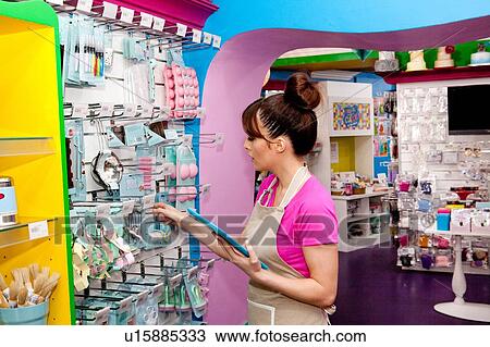 Stock Image - "Portrait of young woman, working in cake shop, counting stock". Fotosearch