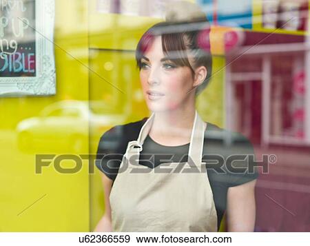 Stock Photo - "Portrait of young woman working in cake shop, taken through shop window". Fotosearch