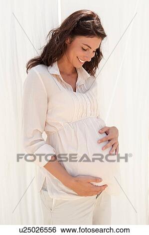 Pregnant mid adult woman looking down at her stomach View Large Photo Image Stock Photograph - Pregnant mid adult woman looking down at her stomach. Fotosearch