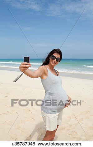 "Pregnant mid adult woman taking smartphone selfie on beach, Cape Verde, Africa" View Large Photo Image Stock Photo - "Pregnant mid adult woman taking smartphone selfie on beach, Cape Verde, Africa". Fotosearch