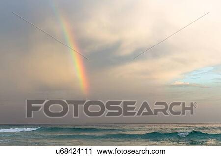 Stock Image - "Rainbow over ocean in cloudy sky, Rio De Janerio, Brazil". Fotosearch