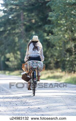 Rear view of woman cycling on forest road with foraging baskets View Large Photo Image Stock Image - Rear view of woman cycling on forest road with foraging baskets. Fotosearch