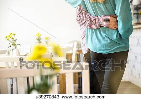 Stock Image - "Rear view of young couples mid section standing in cafe, arm around waist". Fotosearch