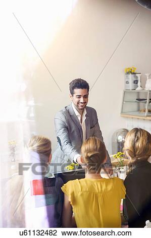 Rear view of young women sitting infront of laptop and young man wearing suit jacket standing smiling View Large Photo Image Stock Image - Rear view of young women sitting infront of laptop and young man wearing suit jacket standing smiling. Fotosearch
