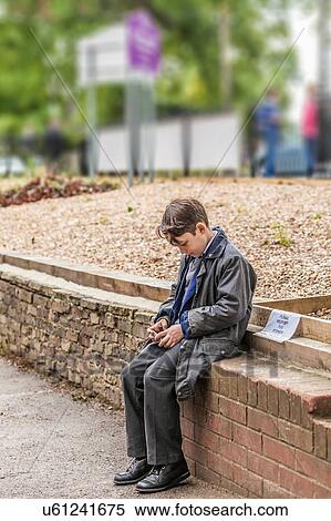 Stock Photography - School boy waiting on brick wall. Fotosearch