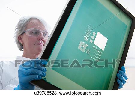 Stock Photo - "Scientist inspects screen printer mesh for graphene ink in graphene processing factory, close up". Fotosearch
