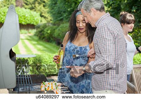 Senior couple cooking on barbecue in garden View Large Photo Image Stock Photo - Senior couple cooking on barbecue in garden. Fotosearch