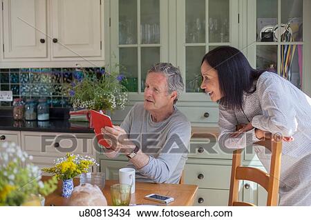 "Senior couple in kitchen, looking at digital tablet" View Large Photo Image Picture - "Senior couple in kitchen, looking at digital tablet". Fotosearch