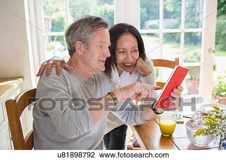 "Senior couple in kitchen, looking at digital tablet" View Large Photo Image Stock Image - "Senior couple in kitchen, looking at digital tablet". Fotosearch