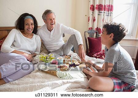 Senior couple relaxing on bed with grandson View Large Photo Image Stock Image - Senior couple relaxing on bed with grandson. Fotosearch