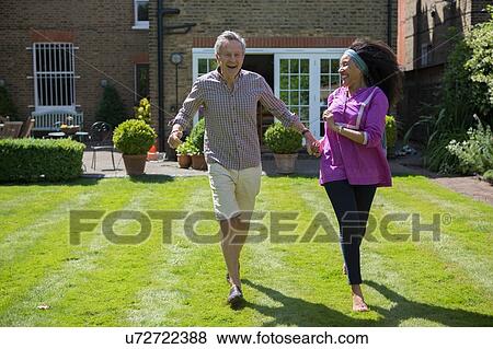 Stock Photo - "Senior couple, running hand in hand, in garden". Fotosearch